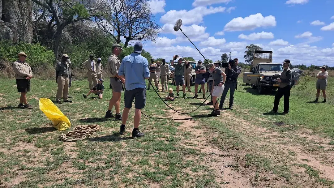 Sound recordist working with a boom in open bush