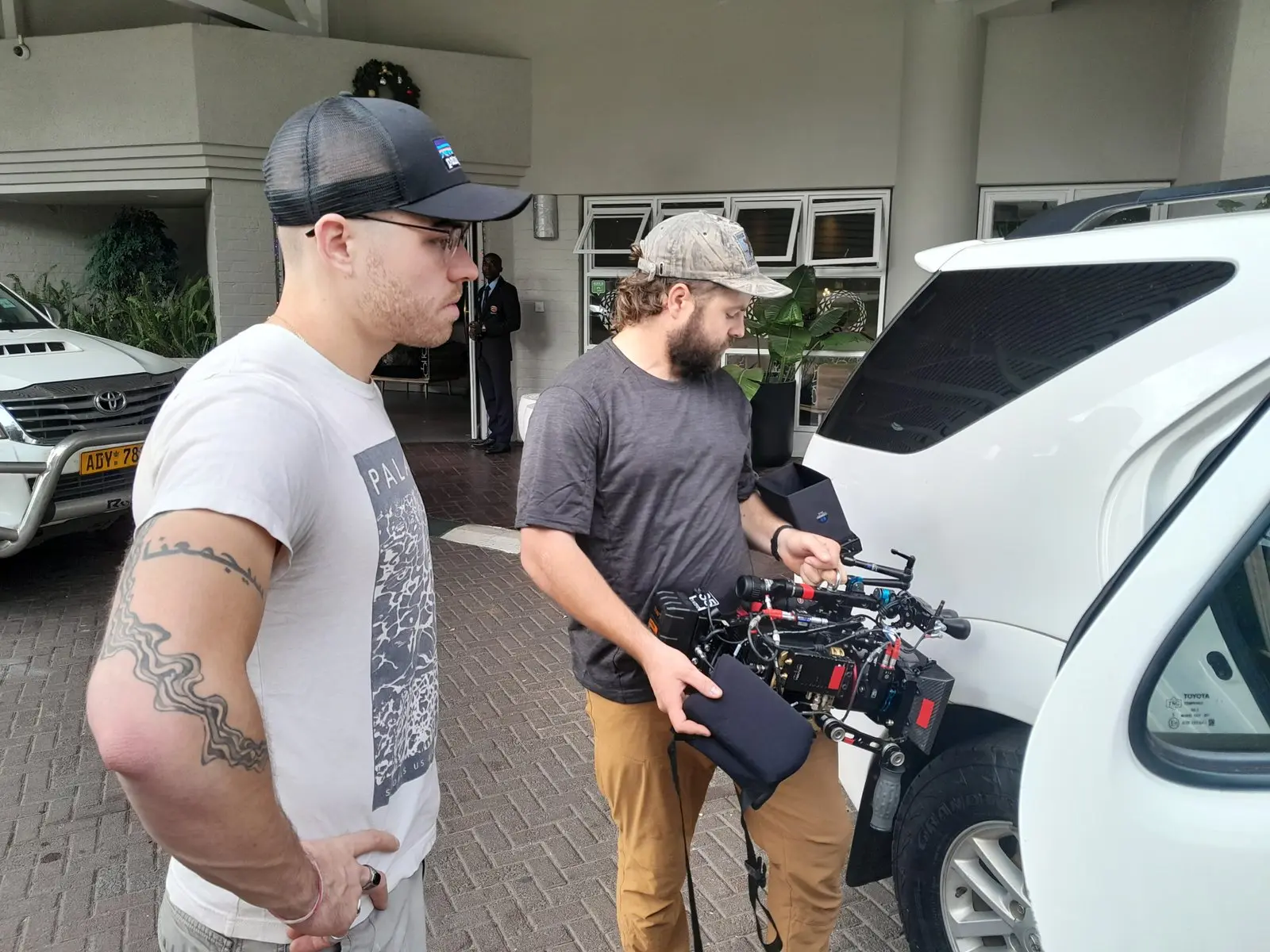 Crew checking a camera rig beside a vehicle